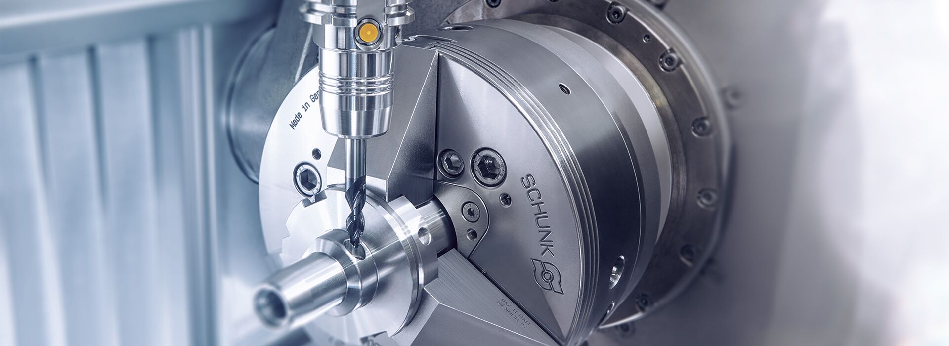 Innovative Präzision: Drehtisch mit Bohrer und Schunk-Logo im Fokus. Ein stimmungsvolles Mood-Bild für Hightech-Fertigung.